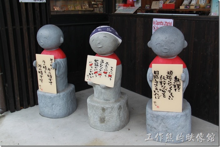 日本北九州-由布院街道。雖然看不懂這三尊小沙彌石像手上拿的牌子寫些什麼，但模樣甚是可愛。還來問了兒子說這三尊小沙彌拿得牌子寫得都是勵志的句子。不要盲目的努力；一個人笑、二人笑、大家笑、地球笑；那個時候就是那個時候。